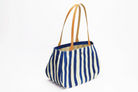Vue de côté sac cabas fourre-tout en toile et cuir - Rayé bleu et blanc. Anse en cuir marron.
